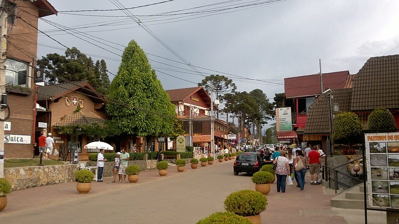 Avenida principal de Monte Verde com lojas, araucárias e casas estilo europeu na serra mineira